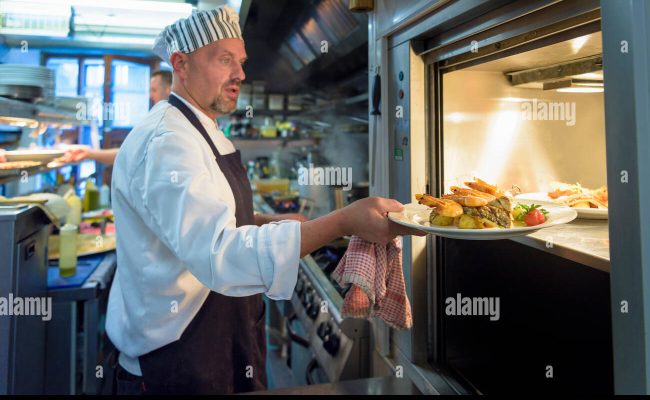 chef-placing-dish-in-lift-in-traditional-italian-restaurant-kitchen-G17PYP